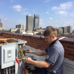 Fred's commercial AC repair technician fixing rooftop unit in city